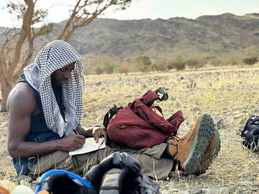 Husain Abdullah writing in a journal during his desert walk